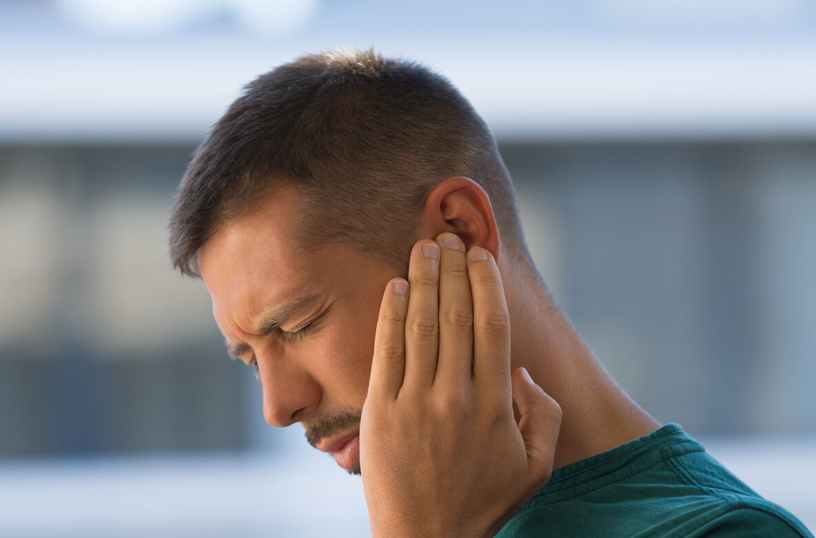 Young man with earache, otitis or tinnitus. Ear inflammation. Man suffering from ear pain