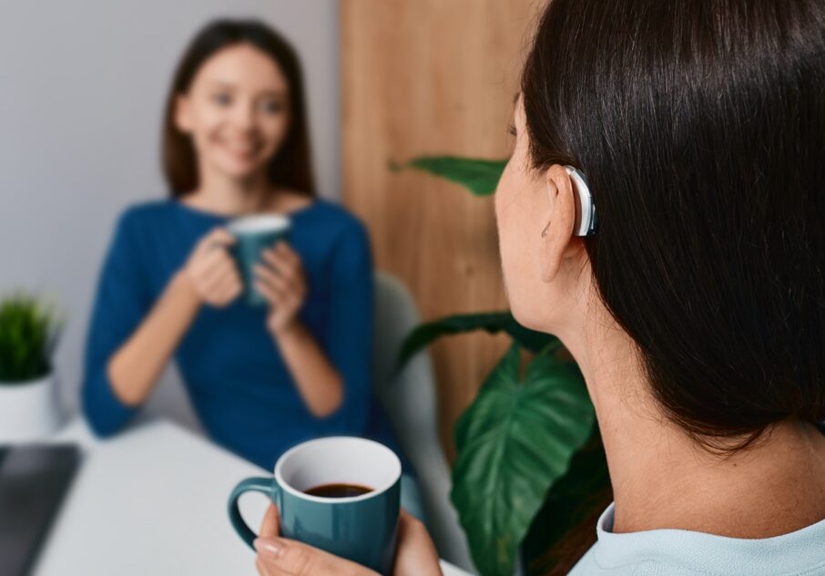 Adult Woman With A Hearing Impairment Uses A Hearing Aid To Comm